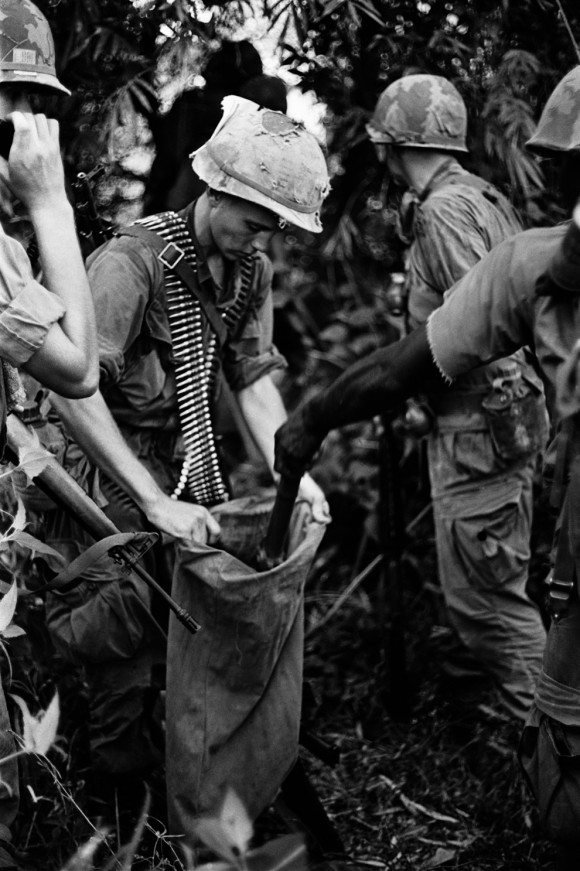Soldados carregam sacos de armas de uma base capturada perto Dau Tieng. Os nomes e data desconhecidos.
