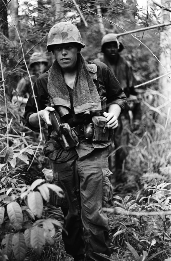Uma fila de soldados em uma patrulha de rotina na selva. Haughey diz que a maioria dos soldados usavam toalhas em torno de seus pescoços, como este fez, para ajudar a combater o suor no calor da selva. Nomes, data e local desconhecidos.
