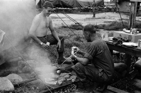 PFC John Kerry (esquerda) e um soldado não identificado fazebdi bifes grelhados e tomando cervejas em Cu Chi. Data desconhecida.