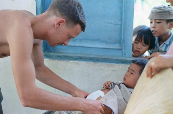 Um médico não identificado que trabalha com um programa de ação cívica médica (MEDCAP) atende a uma criança vietnamita. Nomes, data e local desconhecidos.