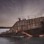 Sobre uma prancha, artista faz grafite em barco naufragado