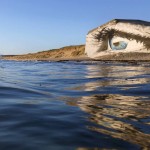 À beira-mar, artista pinta imenso olho azul que parece observar as ondas