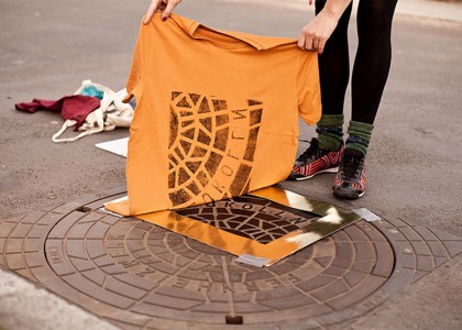 Coletivo de arte estampa camisetas nas ruas, em bueiros e ralos